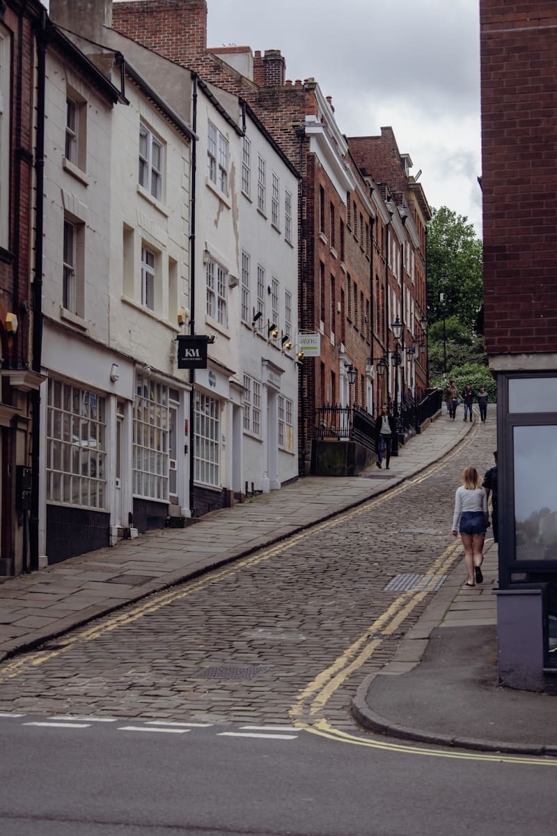 a woman walking down a street next to tall buildings